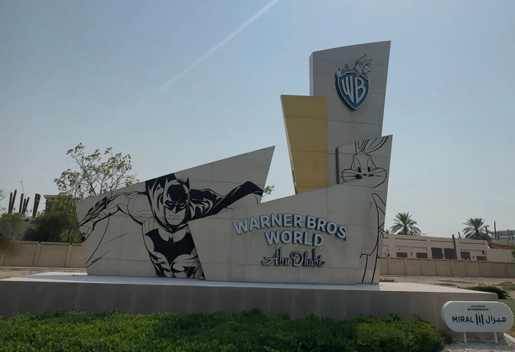 The entrance sign at Warner Bros. World Abu Dhabi, with Batman and Bugs Bunny artwork either side of the Warner Bros. shield